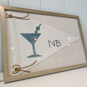 Framed ivory pennant style flag with faded blue martini design and hand stitched NB lettering